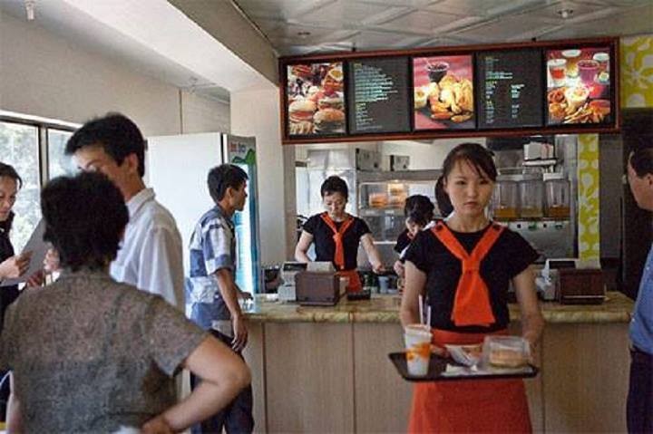 Các nhân viên và thực khách trong một quán bán Hambuger ở Thủ đô Bình Nhưỡng. Cửa hàng bán đồ ăn nhanh này được coi là nét hiện đại ở  đất nước Triều Tiên vốn đóng cửa với thế giới bên ngoài.